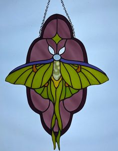 a stained glass hanging decoration with a green and blue butterfly on it's wings