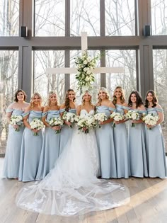 a group of bridesmaids standing in front of a cross