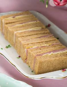 there is a cake that has been cut into slices on a plate with pink flowers in the background