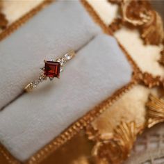 an engagement ring with a red stone surrounded by diamonds