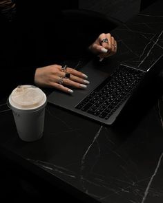 a woman sitting at a table with a laptop and cup of coffee in front of her