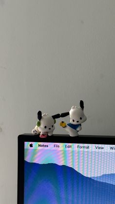 two small figurines sitting on top of a computer screen