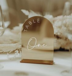 a place card holder sitting on top of a table next to wine glasses and flowers