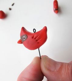 a tiny red bird sitting on top of a wooden stick