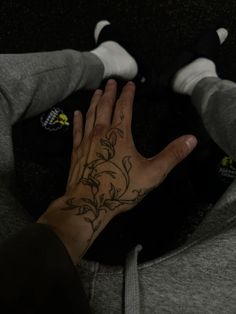 a person's hand with a flower tattoo on their left wrist and right hand