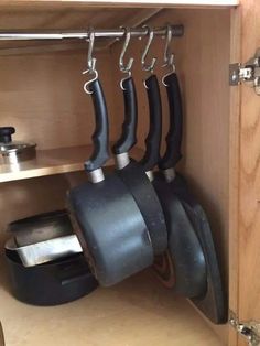 pots and pans are hanging from hooks in the cupboard