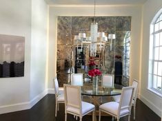 a dining room table with white chairs and a chandelier