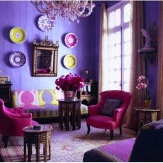 a living room with purple walls and pink chairs in the corner, chandelier hanging from the ceiling