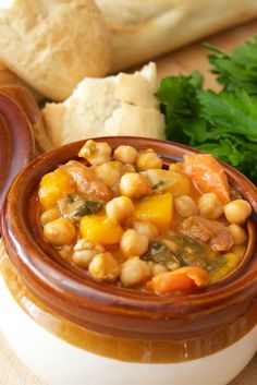 a close up of a bowl of food with bread in the background