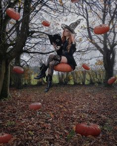 a woman dressed as a witch is sitting on an orange pumpkin chair in the woods