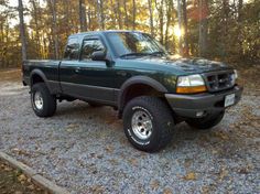 a green pick up truck parked in the woods