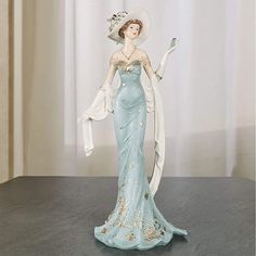 a figurine of a woman in a blue dress and hat holding an umbrella