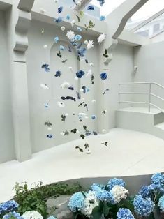 blue and white flowers are floating in the air next to some stairs with railings