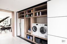 a washer and dryer sitting in front of a wooden shelf filled with bottles