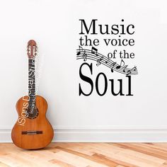 a guitar sitting on the floor in front of a wall that says music the voice of the soul