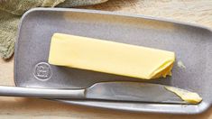 a knife and butter sitting on top of a metal tray next to a piece of cheese