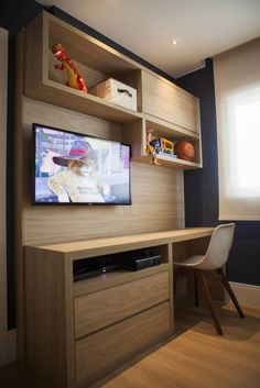 a flat screen tv sitting on top of a wooden shelf next to a desk and chair