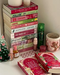 a stack of books sitting on top of a table next to a cup and candle