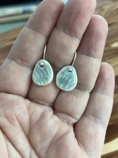 a person is holding two earrings in their hand