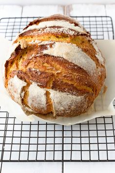 a loaf of bread sitting on top of a white plate next to a cooling rack