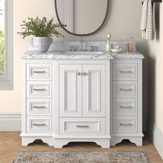 a white bathroom vanity with a round mirror above it and a rug on the floor