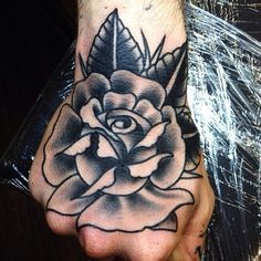 a black and white rose tattoo on the left hand, with an eye in the center