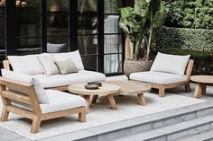 an outdoor living room with white furniture and potted plants