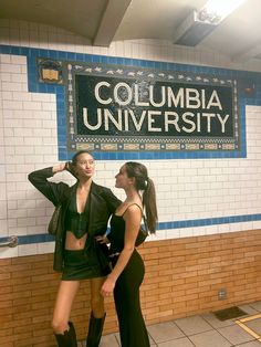 two women standing next to each other in front of a sign that reads columbia university