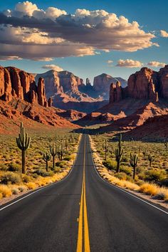 an empty road in the desert with mountains in the background and clouds in the sky