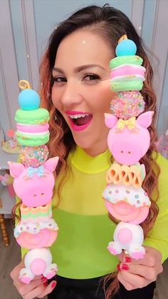 a woman is holding up some cupcakes and doughnuts in front of her face