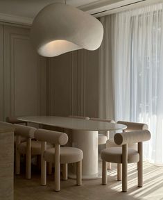 a table and chairs in a room with white curtains