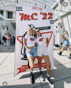 two women standing next to each other in front of a sign that says mc'22