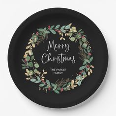 a black paper plate with the words merry christmas on it and greenery wreaths