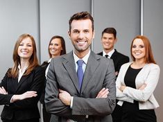 a group of business people standing in front of a wall with their arms crossed and smiling at the camera