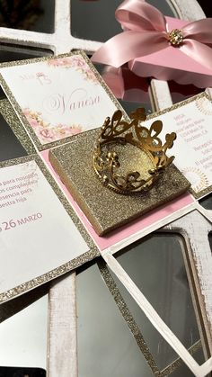 a wedding card with a gold crown on top and pink ribbon tied to it's side