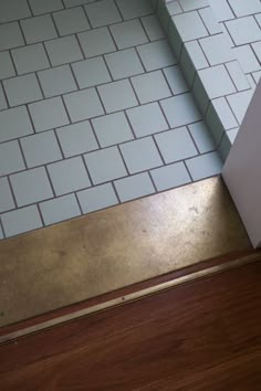 a bathroom with white tile and wood flooring