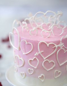 a pink and white cake with hearts on the frosting is sitting on a plate