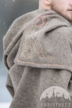 a man wearing a coat with an intricate design on the front and back, standing in the snow