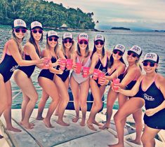 a group of women in swimsuits on a boat posing for a photo together