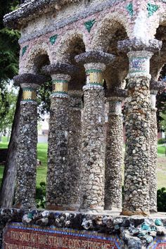 an old building with columns and mosaics on the outside, in front of some trees