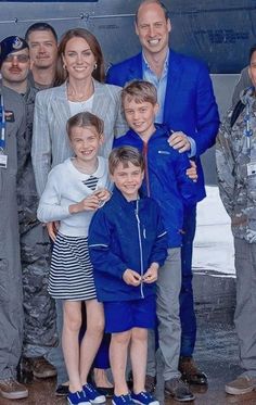 a group of people standing next to each other in front of an airplane on the tarmac