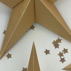 gold stars are arranged in the shape of a star on a white surface with brown paper