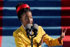 a woman standing in front of a microphone with her hand out to the side and wearing a red headband