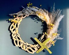 a wreath made out of paper with a cross on the front and some feathers around it