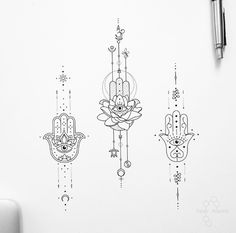 three hamsa tattoos on a white wall next to a pen