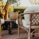 two wicker chairs sitting on top of a brick floor next to a table and chair