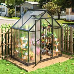 a small greenhouse in the middle of a yard with lots of plants growing inside it