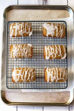 six glazed donuts on a cooling rack with icing drizzled over them