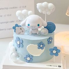 a blue and white cake with an elephant on it's top, surrounded by clouds