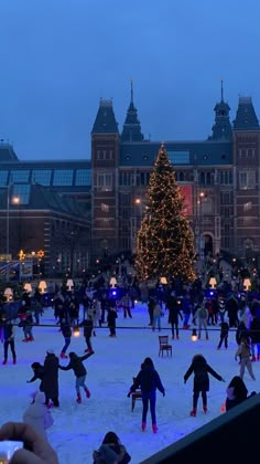 people skating on an ice rink in front of a christmas tree